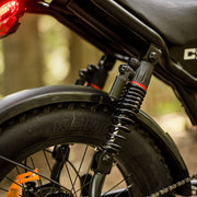 Close-up of a motorcycle wheel with 'Kent' branding, blurred natural background