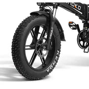 Close-up of a black fat-tire electric bicycle wheel with knobby tread, disc brake, fender, and part of the frame on a white studio background.