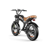 A black electric fat-tire bike with a brown leather saddle, black fenders, and orange accents on the rims and frame details, shown from a three-quarters rear angle on a white background.